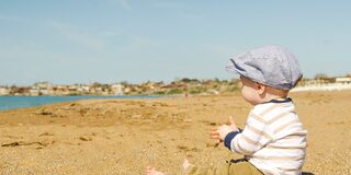 Ein Kind sitzt in der Sonne am Strand