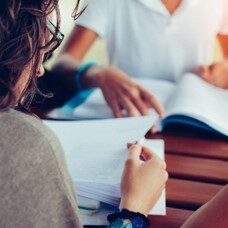 Frau schaut an einem Tisch in Unterlagen