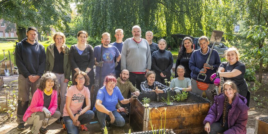 Gruppenbild der fleißigen Mitarbeitenden mit Gartengeräten vor Hochbeeten