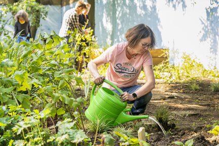 Eine Mitarbeiterin gießt die neugesetzten Pflanzen an