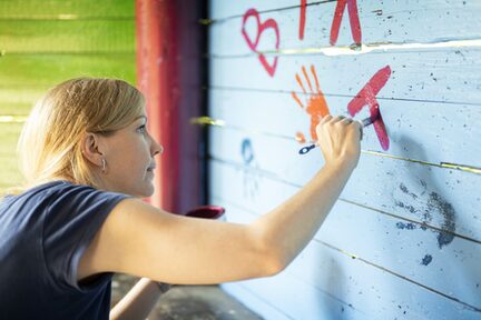 Eine Mitarbeiterin des Unternehmens bemalt eine Holzwand