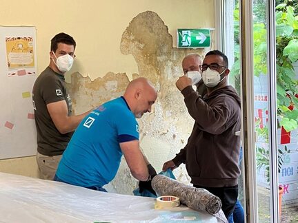 Vier Mitarbeiter bei der Sanierung einer Wand.