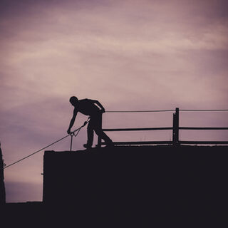 Mann spannt ein Seil im Klettergarten